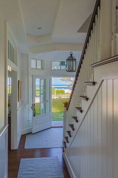 an entry way leading to a house with white walls and wood floors, along with a blue rug on the floor