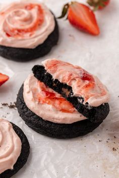 chocolate cookies with cream frosting and strawberries on the top one is half eaten