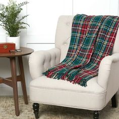 a chair with a plaid blanket on it next to a table and potted plant