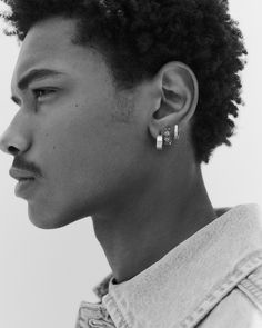 a young man with curly hair wearing earrings