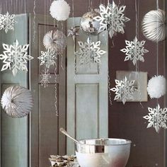 snowflakes are hanging from the ceiling in front of a bowl and spoon on a table