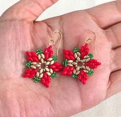 small red and green beaded earrings on a person's hand