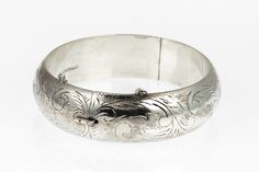 This is a hand engraved vintage sterling silver floral hinged bangle bracelet. The inside is marked Sterling 925. I've tested the piece with acid and guarantee it to be sterling silver. The bracelet is in good condition and closes securely. The outside features a hand chased floral/flower design that is crisp and detailed.  The inside of the bracelet is 2 and 1/4 of an inch long and 2 & 1/8th of an inch wide. Circumference is 6.75 inches. Outside is 5/8 of an inch wide along the band and has a t Luxury Silver Bangle With Intricate Design, Luxury Engraved Sterling Silver Bangle Bracelet, Luxury Antique Sterling Silver Bangle Bracelet, Victorian Silver Engraved Bangle, Victorian Style Engraved Silver Bangle, Victorian Style Silver Engraved Bangle, Victorian Sterling Silver Bracelet, Engraved For Formal Occasions, Victorian Sterling Silver Engraved Wedding Bracelet, Etched Sterling Silver Bangle Bracelet For Wedding