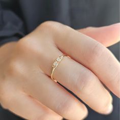 a woman's hand wearing a gold ring with three stones on the middle finger