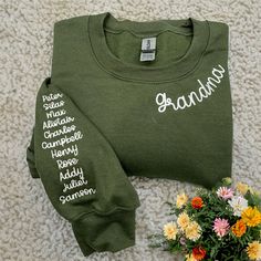 a green shirt with the word grandma written on it next to flowers and a potted plant