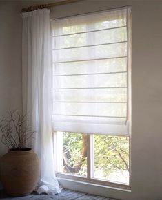 a window with white sheer curtains and a potted plant