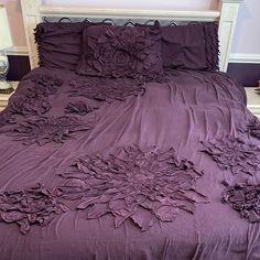 a bed with purple comforter and pillows on it