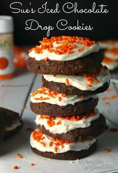 chocolate cookies with white frosting and orange sprinkles are stacked on top of each other