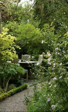 a garden with lots of trees and plants around it, including a table and chairs