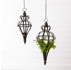 two hanging planters with plants in them on a white wall and wood flooring