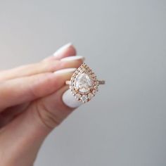 a woman's hand holding an engagement ring with a diamond on the top and side