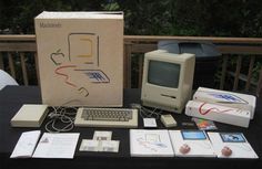 an old computer sitting on top of a table next to other electronic devices and papers