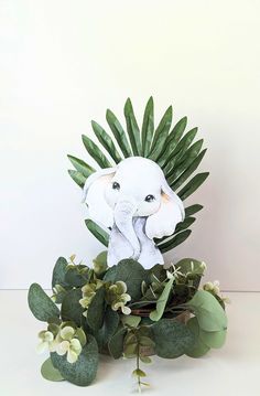 an elephant statue sitting on top of a lush green leafy plant filled with flowers