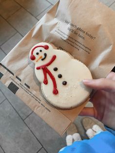 a person holding up a frosted snowman cookie