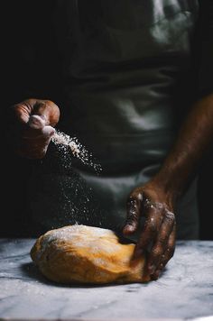 a person sprinkling flour on top of a loaf of bread