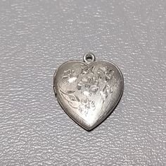 "Victorian Revival vintage Sterling Silver heart picture locket. Front of locket has polished cut out floral design. Locket will hold two pictures. Locket will arrive gift boxed. * HALLMARKS Unmarked, tested positive for silver content. * MEASUREMENTS 7/8\" x 3/4\". * CONDITION In very good to excellent condition. * MATERIALS Sterling Silver." Vintage Heart Pendant Locket Necklace For Wedding, Vintage Heart Locket Necklace Nickel Free, Antique Silver Vintage Locket Necklace For Anniversary, Vintage Antique Silver Locket Necklace For Wedding, Antique Silver Vintage Jewelry For Valentine's Day, Vintage Antique Silver Locket Necklace For Anniversary, Vintage Locket Necklace For Anniversary And Mother's Day, Vintage Locket Necklace With Heart Charm For Wedding, Vintage Antique Silver Jewelry For Valentine's Day