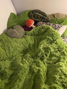 a bed covered in green fluffy blankets and pillows