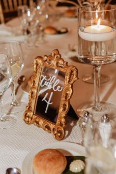 the table is set with wine glasses, silverware, and a gold framed sign