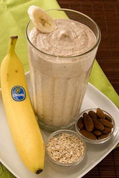 a banana sitting on top of a white plate next to a glass filled with oatmeal