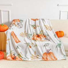 a white couch covered with a blanket and pumpkins