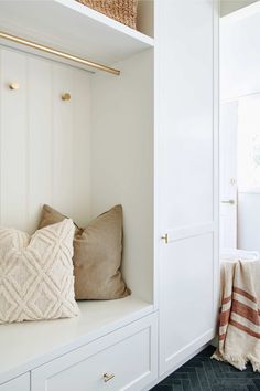 a white closet with some pillows and blankets on the shelf next to it is an entry way