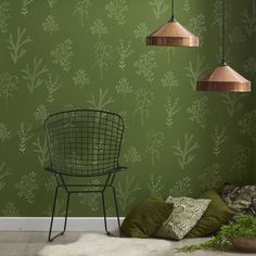 a room with green wallpaper and two lamps hanging from the ceiling over a chair