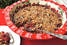 a red and white dish filled with cranberry crisp on top of a table