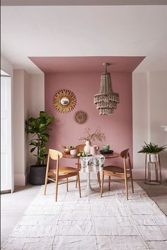 a dining room with pink walls and white rugs on the floor, chandelier hanging from the ceiling