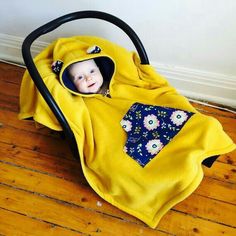 a baby in a yellow blanket sitting in a stroller