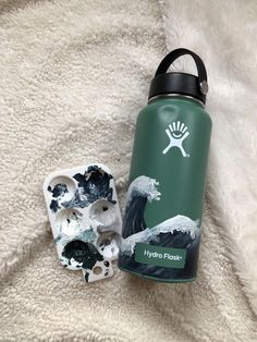 a green hydro flask bottle sitting on top of a white blanket next to a pair of scissors