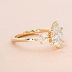 a pear shaped diamond engagement ring on a pink background