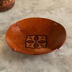 a wooden bowl sitting on top of a table next to two vases with designs