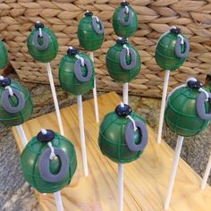 there are many green cake pops on the stick with black and gray decorations in them