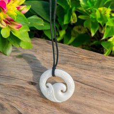 This necklace is meticulously crafted with stunning Polynesian engravings and a wave design, making it truly unique. A skilled artisan carved each pendant with exceptional attention to detail. Complete with an adjustable black waxed cord, ensuring the perfect fit. Wave w/ Engravings Size: Approximately 1-1/4 inch tall x 1-1/4 inches wide Hand carved Includes adjustable cord Material: Bone Handmade Adjustable Engraved Necklaces For Beach, Adjustable Engraved Necklaces For The Beach, Adjustable Carved Round Necklaces, Adjustable Round Carved Necklaces, Adjustable Carved Round Necklace, Artisan Carved Adjustable Jewelry, Carved Pendant Necklace Adjustable, Adjustable Carved Pendant Necklaces, Adjustable Carved Pendant Necklace