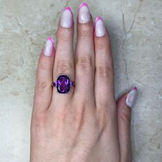 The Nassau ring features an elongated cushion-cut amethyst that is accented by two amethysts on either side. The 14k yellow gold mounting features a scroll motif on the gallery and diamonds along the shoulders.
The center amethyst is 14mm x 10mm and weighs 6.07 carats. The diamonds have a total carat weight of 0.05 carats.
This ring can be resized to any finger size at no extra cost.
If you have any questions about the Nassau ring, please feel free to contact us. Luxury Purple Rectangular Amethyst Ring, Luxury Purple Amethyst Rectangular Ring, Luxury Purple Amethyst Ring, Rectangular Shape, Luxury Rectangular Amethyst Ring, Purple Emerald Cut Amethyst Ring With Gemstone Accents, Purple Amethyst Ring With Emerald Cut And Gemstone Accents, Rectangular Purple Amethyst Ring With Accent Stones, Purple Amethyst Ring With Accent Stones, Rectangular Shape, Rectangular Amethyst Gemstone Ring