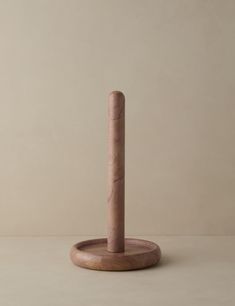 a small wooden object on a white surface with a beige wall in the back ground