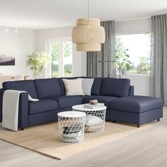 a living room with blue couches and white tables in front of large windows that look out onto the outdoors