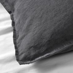 a black and white photo of a pillow on top of a bed with linens