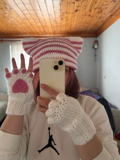 a woman taking a selfie in front of her phone wearing gloves and a hat