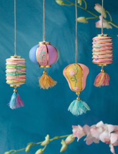 colorful paper lanterns hanging from strings with flowers in the foreground and blue wall behind them