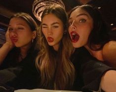 three beautiful young women sitting next to each other in front of a cake with candles on it