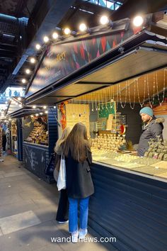 a woman standing in front of a store filled with lots of gold and other items