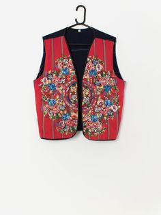 Vintage red embroidered vest with bright florals. This 70s bright red and navy blue vest features a bold embroidered floral pattern on the front, has edge to edge with no fastenings and is made from a heavyweight cotton. Our recommended size: XL Label says: XL Condition: Good. Small marks on the back. Please see last image (not colour accurate)   Material: 100% cotton Measurements in inches: Pit to pit: 21.5 Shoulders: 17.5 Front length: 24 Back Length: 23.5 Hem: 22 We recommend that you compare Folk Style Sleeveless Summer Vest, Sleeveless Folk Style Summer Vest, Folk Style Sleeveless Vest With Floral Embroidery, Sleeveless Folk Vest With Floral Embroidery, Red Embroidered Sleeveless Vest, Spring Folk Festival Vest, Retro Red Sleeveless Vest, Red Sleeveless Retro Vest, Folk Style Multicolor Vest For Spring