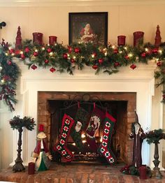 a fireplace decorated for christmas with stockings and candles