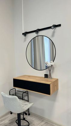 a mirror hanging on the wall next to a table with a chair in front of it