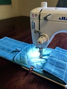 a sewing machine sitting on top of a wooden table next to blue towels and a light