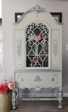 a white china cabinet with flowers on top