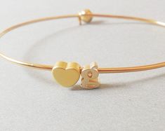 Hearts available for 1st or 2nd charm, or both charms can be letters. This charming bracelet is made with one tiny lowercase gold plated letter charms, an gold plated heart charm, and a gold plated self-closure bangle bracelet. Simple enough for everyday wear and looks great stacked and layered. Also makes great gifts for bridal parties, birthdays, graduation or any special event! This is super sweet gold plated bracelet you can wear everyday! It is definitely a great layering piece also ❤ Bangl Gold Charm Bracelet With Heart Charm As Gift, Gold Charm Bracelet With Heart Charm For Mother's Day, Minimalist Gold Charm Bracelet With Heart, Personalized Gold Charm Bracelet For Everyday Wear, Gold Charm Bracelet For Mother's Day, Gold Charm Bracelet With Heart Charm And Adjustable Fit, Gold Heart-shaped Name Bracelet For Everyday, Adjustable Gold Charm Bracelet With Initials, Dainty Gold Charm Bracelet For Personalized Gift