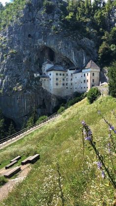 a large white building sitting on top of a lush green hillside next to a cliff