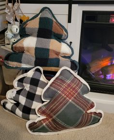 pillows and blankets are stacked in front of a fireplace with a fire place behind them